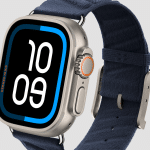 The Apple Watch boasts a titanium case, displaying time at 10:09. It features a dark blue Hermès fabric strap and an orange accent on the side button. The watch face highlights bold, white numerals on a black background with a distinct blue outline.