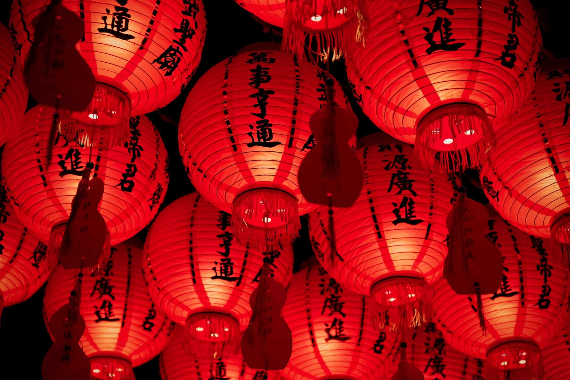 Bright red Chinese lanterns with black calligraphy hang closely together, illuminated from within. The warm light creates a festive atmosphere—perfect for sightseeing or sensing the vibrant traditions while visiting Taiwan.